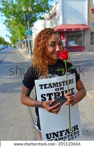 BAKERSFIELD, CA-JULY 15, 2014: After six months failed negotiations the teamsters union strikes the Golden Empire Transit District. An unidentified woman stops to smell a rose.