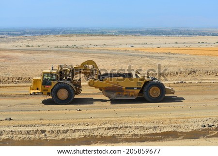 BAKERSFIELD, CA-JULY 18, 2014: A motor scraper helps to bring the road base up to grade during the project to widen State Route 178.