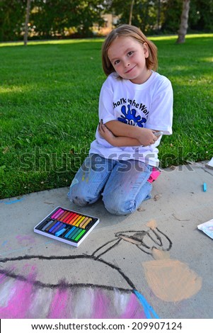 TEHACHAPI, CA - AUGUST 9, 2014: Lillian Bouldin, an elementary school student, shows a lot of enthusiasm for her entry in the annual Chalk on the Walk art contest.