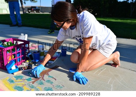 TEHACHAPI, CA - AUGUST 9, 2014: Lori Martin has already laid out here drawing on the sidewalk and begins to add color to her creation for the annual Chalk on the Walk art contest.