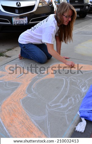 TEHACHAPI, CA - AUGUST 9, 2014: Kyla Hansen has already laid out here drawing on the sidewalk and is beginning to add color to her creation for the annual Chalk on the Walk art contest.