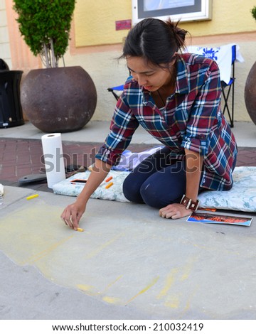 TEHACHAPI, CA - AUGUST 9, 2014: Saya Novinger has already laid out here drawing on the sidewalk prior to adding color to her creation for the annual Chalk on the Walk art contest.