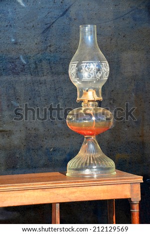 An old fashioned oil lamp is displayed in the window of an antique store.