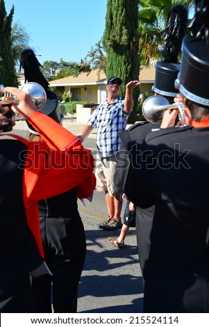 WASCO, CA - SEPTEMBER 6, 2014: Band director Greg Sparks (blue shirt) tunes up the Wasco Union High School musicians before the start of the Festival of Roses parade.
