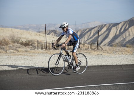 BAKERSFIELD, CA - NOVEMBER 16, 2014: An unidentified male contestant has completed a run and now speeds over the course during  the cycling portion of the Kern River Duathlon.