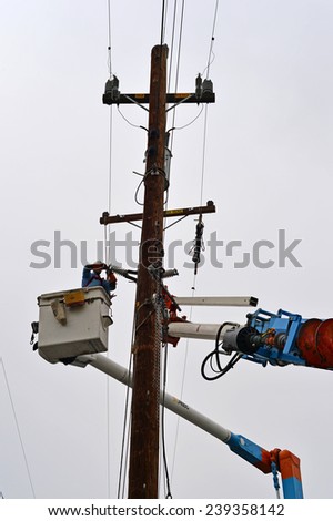 BAKERSFIELD, CA - DECEMBER 21, 2014: The local utility company is replacing a wood pole. An electrician works from the basket of a man lift during the high voltage cutover.