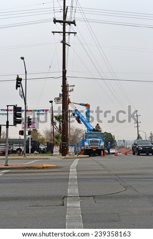 BAKERSFIELD, CA - DECEMBER 21, 2014: The local utility company is replacing a wood pole. A three  man crew of electricians with man lift and high voltage equipment is making the switch.