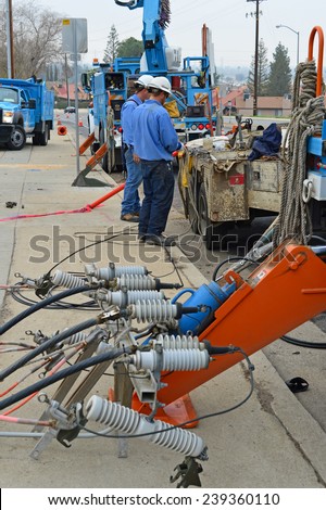 BAKERSFIELD, CA - DECEMBER 21, 2014: The local utility company is replacing a wood pole. A three  man crew of electricians with man lift and high voltage equipment is making the switch.
