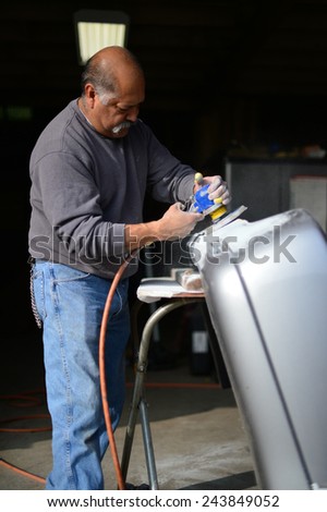 BAKERSFIELD, CA - JAN 13, 2015: Jesse Castenada applies his skill with the sanding wheel to an auto part at a local body shop.