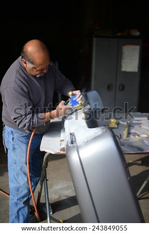 BAKERSFIELD, CA - JAN 13, 2015: Jesse Castenada applies his skill with the sanding wheel to an auto part at a local body shop.