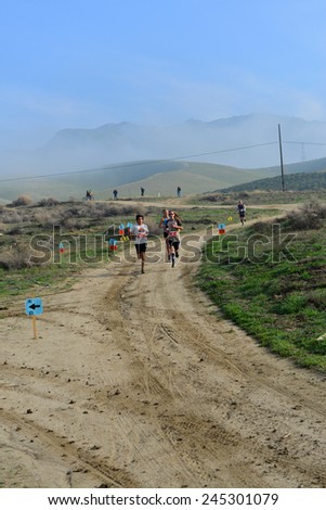 BAKERSFIELD, CA - JAN 17, 2015: Contestants run the first stage of the Rio Bravo Rumble biathlon (running and mountain biking) on a scenic dirt trail.