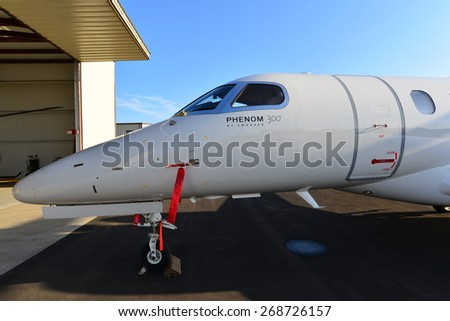 SHAFTER, CA - APR 11, 2015: This corporate jet, an Embraer Phenom 300, is parked on the ramp, ready for the hangar doors to open and routine maintenance to begin.