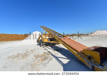 Materials handling equipment and conveyor belts work amid piles of borax near an agricultural chemical plant.