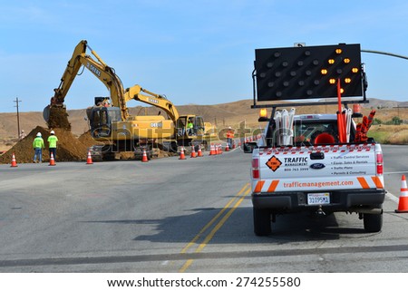 BAKERSFIELD, CA - APR 29, 2015: Traffic must be managed while heavy equipment is employed to lay new sewer pipe across busy State Route 178.