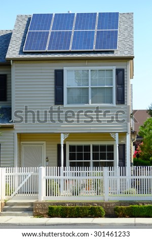 A two story residence has used available roof space to mount solar panels to defray utility company  electrical charges.