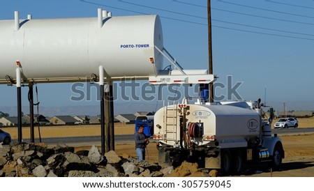 BAKERSFIELD, CA - AUGUST 11, 2015 : A water truck is loading on a construction job site after which it will spray the bare ground for dust abatement.