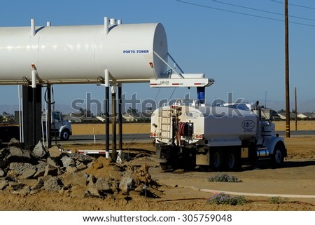 BAKERSFIELD, CA - AUGUST 11, 2015 : A water truck is loading on a construction job site after which it will spray the bare ground for dust abatement.