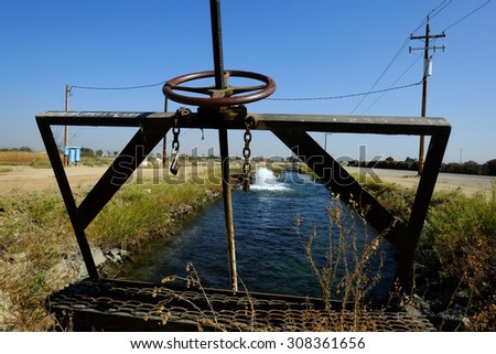 KERN COUNTY, CA - AUG 20, 2015: A sluice gate controls water levels and flows as precious ground water is pumped into an irrigation canal during drought conditions.