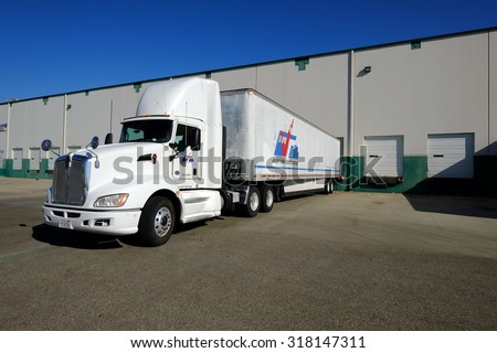 SHAFTER, CA - SEPTEMBER 17, 2015: This large industrial warehouse complex is a transportation hub for Central California. A tractor trailer rig unloads its cargo at the loading dock.