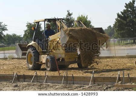 A backhoe with bucket loader attachment spreads dirt on construction job site