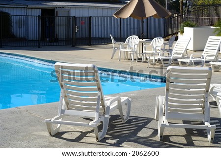 White chairs arranged around a blue swimming pool