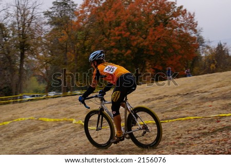 A cross country bicycle (cyclocross) racer under cloudy autumn skies