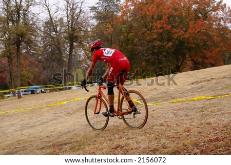 A cross country bicycle (cyclocross) racer under cloudy autumn skies