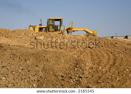 Heavy construction equipment working on a mound of dirt