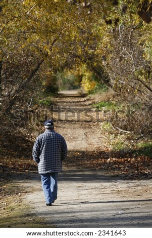 Man walking down a dirt path surrounded by fall color