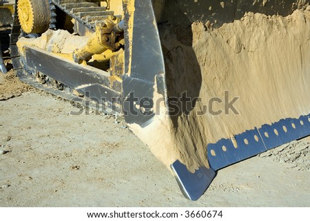 The big blade of a bulldozer is encrusted with dirt