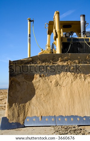 The big blade of a bulldozer is encrusted with dirt