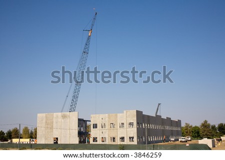 Large panels of precast concrete are tilted up with cranes to form the walls of a large building