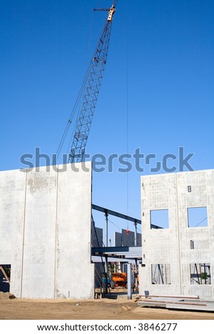 Large panels of precast concrete are tilted up with cranes to form the walls of a large building