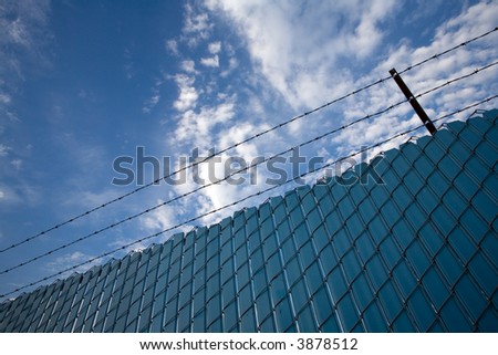 Chain link fence with privacy screens and barbed wire