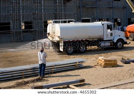 A water truck sprays construction job site for dust abatement
