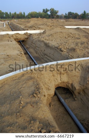 Underground electrical conduit passes under curbs in ditch on construction project