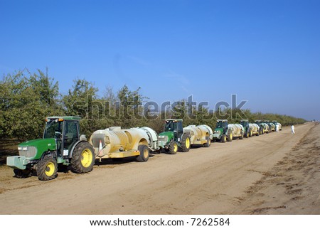 Tractors and insecticide spraying trailers in almond groves, San Joaquin Valley, California