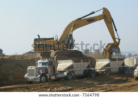 Power shovel loads trucks on site of new highway construction