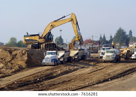 Power shovel loads trucks on site of new highway construction