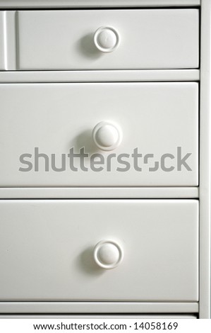 Background or texture: White painted drawers and pull knobs in chest