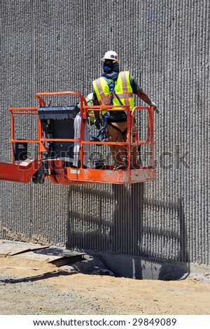 Construction workers use chemicals to strip away form residue on decorative concrete retaining wall