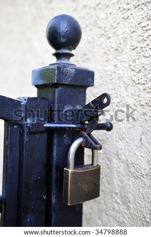 Closed padlock securing a wrought iron gate