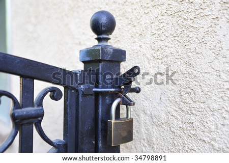 Closed padlock securing a wrought iron gate