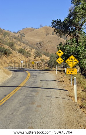 A narrow twisting mountain road shows plenty of warning signs