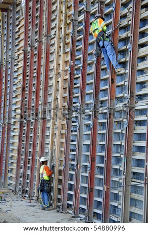 Workmen build gigantic concrete form used on major freeway construction project