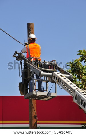 Communications company workman installs overhead lines working from manlift