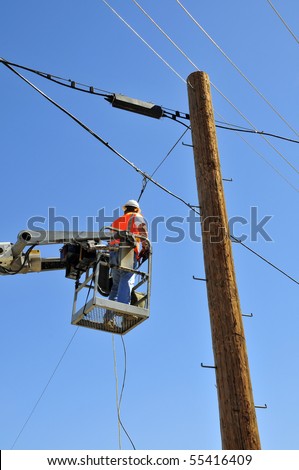 Communications company workman installs overhead lines working from manlift