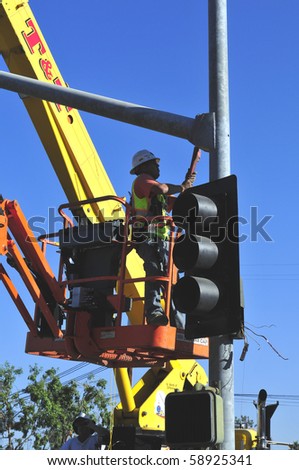 BAKERSFIELD, CA - AUG 12: Electricians completely replace traffic signals, poles and mast arms at a major intersection on August 12, 2010, at Bakersfield, California. Mast arm is bolted to the pole.