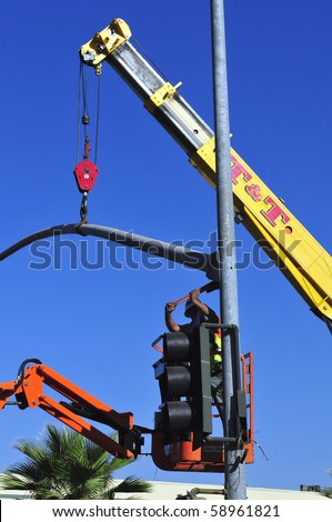 BAKERSFIELD, CA - AUG 12: Electricians completely replace traffic signals, poles and mast arms at a major intersection on August 12, 2010, at Bakersfield, California. Mast arm is positioned.