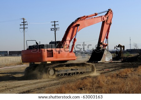 Construction job site: Digging bucket attached to articulated boom on tracked equipment